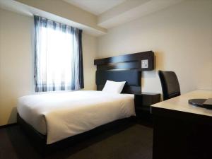 a bedroom with a bed and a window and a desk at Green Rich Hotel Osaka Airport in Ikeda