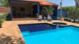 a blue swimming pool in front of a house at Chacara vila geovana suites in Pirenópolis