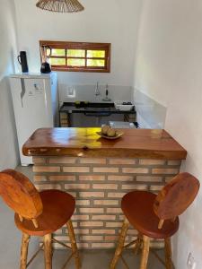 cocina con encimera de madera y 2 sillas en CHALÉS MELGAÇO, en Cumuruxatiba