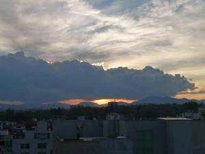 una puesta de sol sobre una ciudad con montañas en el fondo en Apartamento cerca de Centro CitiBanamex en Ciudad de México