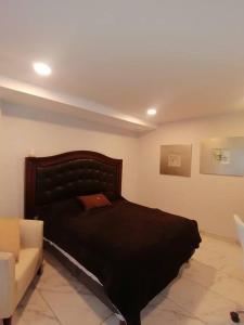een slaapkamer met een zwart bed en een bank bij Apartamento cerca de Centro CitiBanamex in Mexico-Stad
