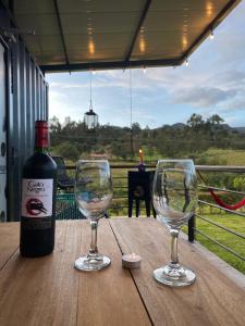 uma garrafa de vinho e dois copos de vinho numa mesa em Acogedor y moderno Glamping en container, 10 min del centro em Chiquinquirá