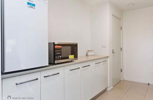 a kitchen with white cabinets and a microwave at Apollo Blue Oceanview Unit 1- B Free WIFI in Apollo Bay