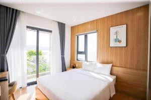 1 dormitorio con cama blanca y ventana en HAKU Boutique Hotel Quy Nhơn, en Quy Nhon