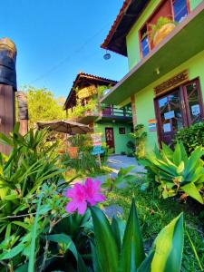 a pink flower in front of a house at Pousada Bem te vi in Garopaba