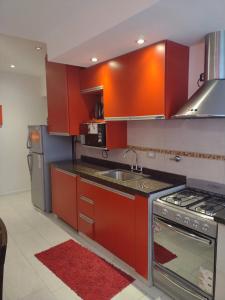 cocina con armarios rojos, fregadero y fogones en 9 ¾ Apartamentos VIP en La Falda