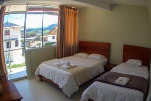 een hotelkamer met 2 bedden en een groot raam bij Hospedaje San Antonio in Oxapampa