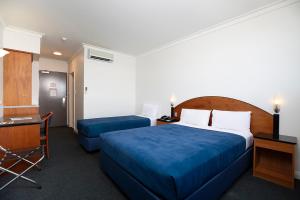ein Hotelzimmer mit einem Bett, einem Schreibtisch, einem Bett und einem Schreibtisch in der Unterkunft Great Southern Hotel Perth in Perth