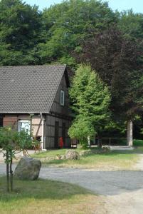 ein Haus mit einem Baum und einem Felsen davor in der Unterkunft Barock Hengst Hof in Niederhaverbeck