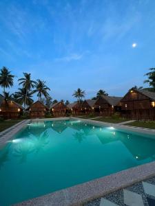 a large swimming pool with blue water at night at Nipoh Beach Cottage in Kijal