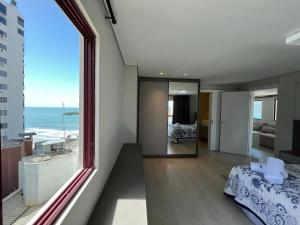 1 dormitorio con vistas al océano desde una ventana en PS01- Cobertura Duplex| Pé na Areia| Churrasqueira, en Balneário Camboriú