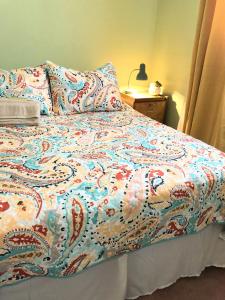 una cama con un edredón colorido encima en Country haven room with desk near wineries, en Hemet