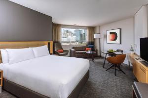 a hotel room with a bed and a living room at Novotel Sydney Darling Harbour in Sydney