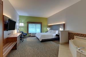 CampbellsvilleにあるHoliday Inn Express Campbellsville, an IHG Hotelのベッド、テレビ、バスタブが備わるホテルルームです。