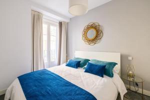 een slaapkamer met een groot bed met blauwe kussens bij Amazing flat 5 balconies in Chueca - Gran Via in Madrid