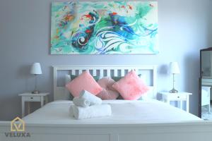 a bedroom with a white bed with pink pillows at Veluxa - Renovated! La Maison des Artist in Dubai