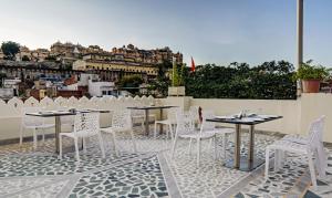 eine Gruppe von Tischen und Stühlen auf einer Terrasse in der Unterkunft Treebo Trend Jheel Mahal in Udaipur