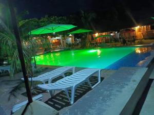 a pool with chairs and umbrellas at night at RRJ's BEACH RESORT in Oslob