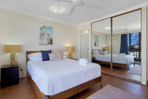 1 dormitorio con 2 camas y un espejo grande en Beach Palms Holiday Apartments, en Gold Coast