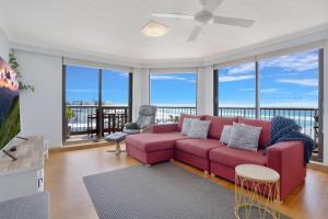a living room with a red couch and large windows at Beach Palms Holiday Apartments in Gold Coast
