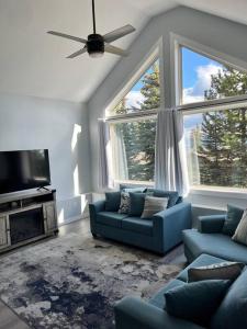 a living room with two blue couches and two large windows at Bearcub Chalet in Big White