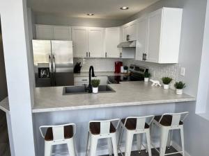 a kitchen with white cabinets and a counter with stools at Bearcub Chalet in Big White