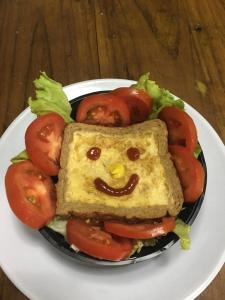 un sándwich con una cara hecha de tomates en un plato en Tamarindo Hostel, en San Pedro Sula