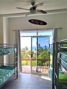 a room with bunk beds and a door to a balcony at Fare Arana Mooréa Guesthouse in Atiha