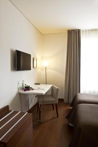 
a room with a table, chairs, and a television at Ribeira do Porto Hotel in Porto
