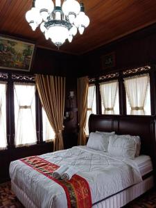 a bedroom with a bed with a chandelier and windows at Grand Malaka Ethical Hotel in Palembang