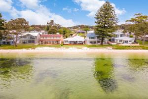 a body of water with houses in the background at Beached Inn Spacious beach front house in Salamander Bay