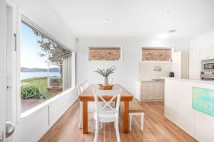 a kitchen and dining room with a table and chairs at Beached Inn Spacious beach front house in Salamander Bay