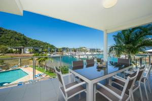 uma varanda com uma mesa e cadeiras com vista para uma marina em Beachside Magnetic Harbour Apartments em Nelly Bay