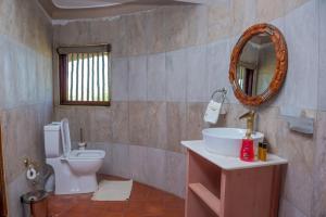 a bathroom with a toilet and a sink and a mirror at Tilenga Safari Lodge in Arua