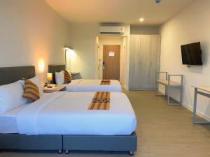 a hotel room with two beds and a television at GRAND PA Hotel&Resort Lamphun Chiang Mai in Lamphun