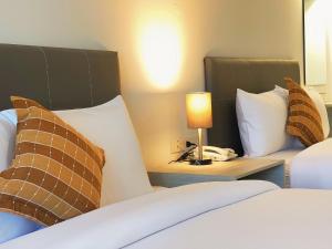 une chambre d'hôtel avec deux lits et une lampe sur une table dans l'établissement GRAND PA Hotel&Resort Lamphun Chiang Mai, à Lamphun