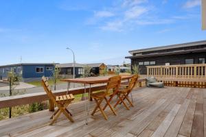 a wooden table and chairs on a wooden deck at Sandy Retreat - Waihi Beach Holiday Home in Waihi Beach