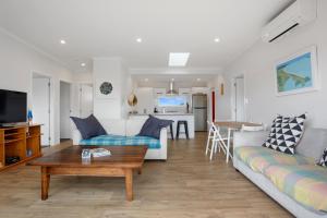 a living room with a couch and a table at Sandy Retreat - Waihi Beach Holiday Home in Waihi Beach