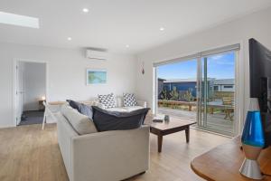 a living room with a couch and a table at Sandy Retreat - Waihi Beach Holiday Home in Waihi Beach