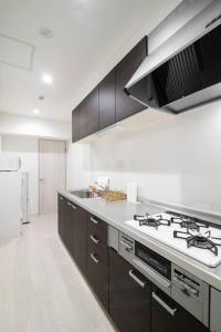 - une cuisine blanche avec cuisinière et évier dans l'établissement HIRO BUILDING Apartment Stay, à Fukuoka