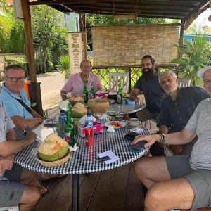 een groep mannen die rond een tafel zitten bij PIMA Homestay in Pesanggaran
