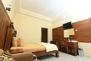 a bedroom with a bed and a desk and a television at MCM HOTEL WISATA BOJONEGORO in Bojonegoro