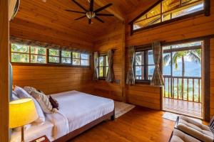 a bedroom with a bed in a room with windows at amã Stays & Trails The Malabar Villa Heliconia, Kozhikode in Wayanad