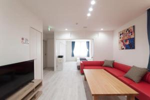- un salon avec un canapé rouge et une télévision dans l'établissement HIRO BUILDING Apartment Stay, à Fukuoka
