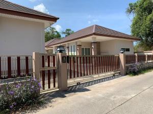 une maison avec une clôture en bois et des fleurs violettes dans l'établissement W house Ranong 2bedroom villa 8/9, à Ranong