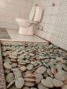 ein Bad mit Felsen auf dem Boden vor einem WC in der Unterkunft Legend guest house in Kelimutu