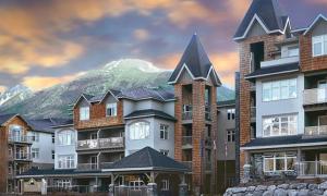 a group of buildings with a mountain in the background at Windtower Lodge FullKitchen-Kingbed Suite-MntView-UGParking-Walk2DT in Canmore