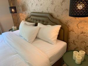 a bed with white pillows and two candles on a table at W House Ranong 1 Bedroom villa 8/10 in Ban Lum Than