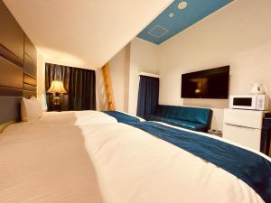 名護市にあるフェニックスパークホテルの白い大型ベッドとソファが備わるホテルルームです。