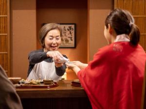 una mujer sentada en una mesa delante de una mujer en Hakkei, en Maniwa